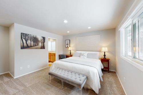 a white bedroom with a large bed and a bench at Mission Getaway in Spokane Valley