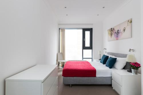 Dormitorio blanco con cama y manta roja en City Apartments, en Londres