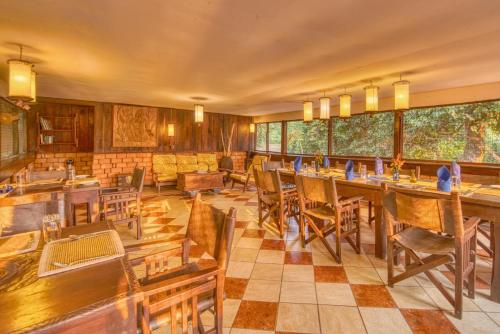 una sala da pranzo con tavoli e sedie in legno di Mbali Mbali Gombe Lodge a Kasekera