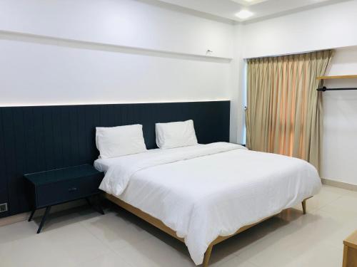 1 dormitorio con 1 cama grande con sábanas blancas en Hamsun Apart Hotel Clifton en Karachi