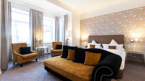 um quarto de hotel com uma cama e um sofá em Parkhotel Bilm im Glück am Stadtrand Hannovers em Sehnde