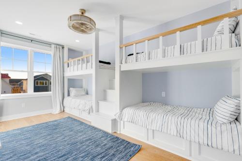 a white bedroom with two bunk beds and a blue rug at Town of Bethany Beach --- 220 4th Street in Bethany Beach