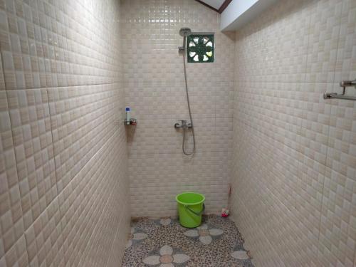 ein Badezimmer mit einer Dusche und einem grünen Eimer in der Unterkunft Bale Bali Cottage 2 in Ubud