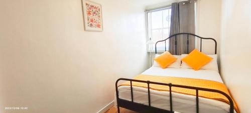 ein Schlafzimmer mit einem Bett mit orangefarbenen Kissen und einem Fenster in der Unterkunft Bluebell 3 at Regent's Park in London
