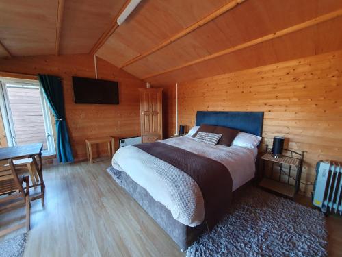 ein Schlafzimmer mit einem Bett in einer Holzhütte in der Unterkunft The Cabin @Tenacre in Boston