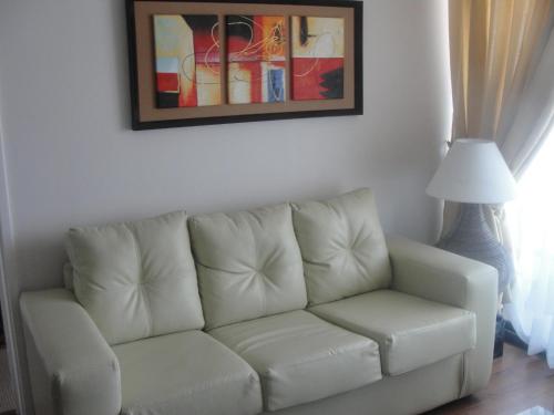 a white couch in a living room with a picture on the wall at Apartment Las Heras in Santiago
