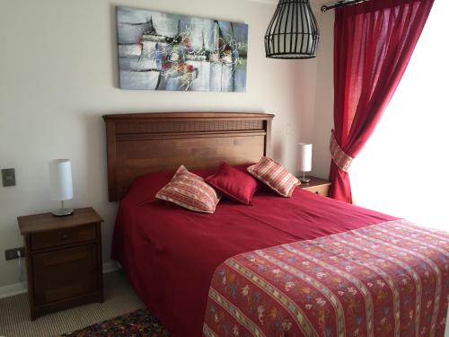 a bedroom with a bed with red sheets and pillows at Apartment Las Heras in Santiago