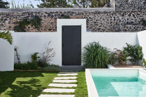 a door to a house with a yard with a swimming pool at Katikies Garden Santorini - The Leading Hotels Of The World in Fira