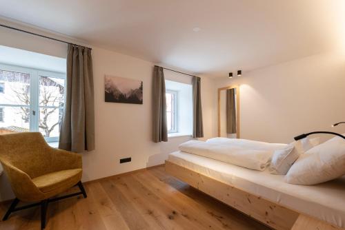 a bedroom with a large bed and a chair at Residence Kugler in San Candido