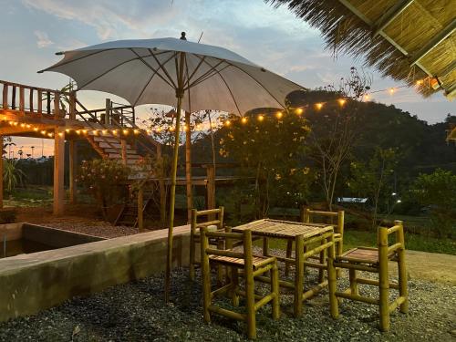 a table and chairs with an umbrella and lights at ดอยผาหมอก โฮมสเตย์ น่าน 