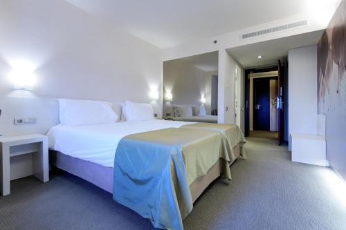 a hotel room with a large white bed and a hallway at Ramada Plaza by Wyndham Bucharest Convention Center in Bucharest