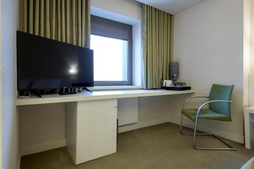 a desk with a television and a chair in a room at Ramada Plaza by Wyndham Bucharest Convention Center in Bucharest