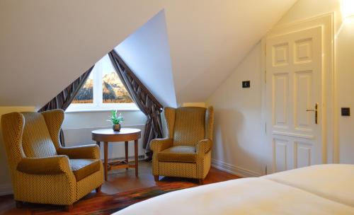a bedroom with two chairs and a bed and a window at Grand Hotel Kempinski High Tatras in Štrbské Pleso