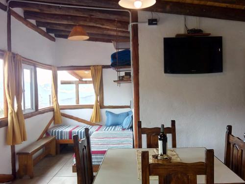 sala de estar con mesa, sofá y TV en Camino & Piedra - Cabaña de Montaña en Potrerillos