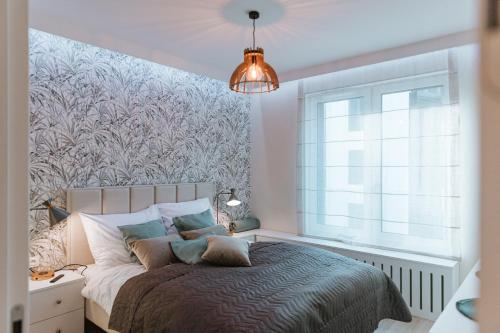 Un dormitorio con una cama y una ventana grande. en ApartView Porto Łeba by Rent like home, en Łeba