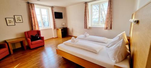 um quarto com uma cama com lençóis brancos e 2 janelas em Wirtshaus Leindl em Krems an der Donau