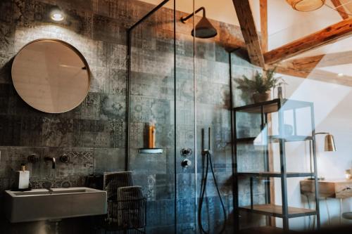 ein Bad mit einer Dusche, einem Waschbecken und einem Spiegel in der Unterkunft Zimmerei in Murten