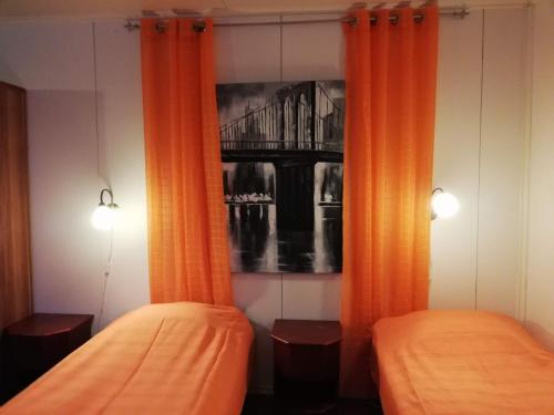 2 camas en una habitación con cortinas naranjas en Kodit Tuulikinkatu, en Mikkeli