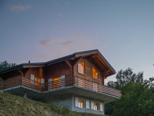 una casa de madera en una colina con sus luces encendidas en Chalet le Fauconnier, en La Tzoumaz