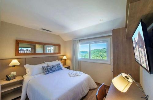 a bedroom with a large bed and a window at Quarto/Apartamento no Wyndham Gramado Termas Resort in Gramado