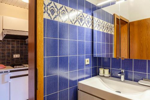 ein blau gefliestes Bad mit einem Waschbecken und einem Spiegel in der Unterkunft Haus Excelsior Top 3 in Seefeld in Tirol