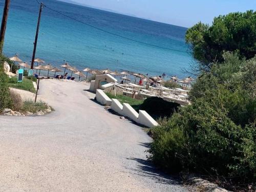 a road leading to a beach with umbrellas and the ocean at Villa Evita Garden Floor Suite in Afitos