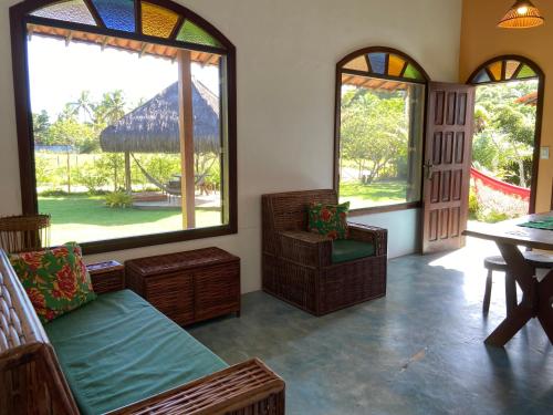sala de estar con 2 ventanas, mesa y sillas en Cores do Mar Cabanas, Taipu de Fora, en Barra Grande