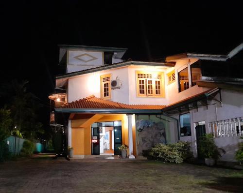 a white house with lights on it at night at Madara Hotel in Horana