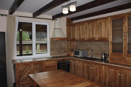 cocina con armarios de madera, mesa y ventana en Чорногірський Вітер en Verkhovyna