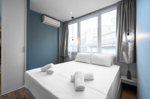 ein Schlafzimmer mit einem weißen Bett und Handtüchern darauf in der Unterkunft Bliss Apartments, The Luxury Suites in Thessaloniki
