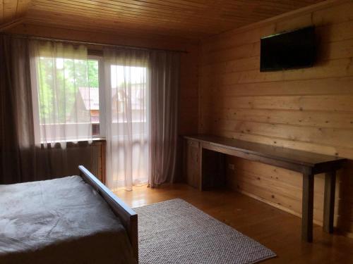 a bedroom with a bed and a desk and a window at Чорногірський Вітер in Verkhovyna