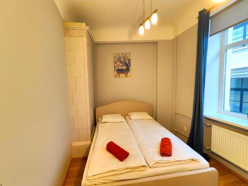 a bed in a room with two red pillows on it at Gleznotaju Old Town Two Bedroom Apartment in Rīga