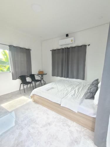 1 dormitorio blanco con 1 cama y 2 sillas en ไร่ดง โฮมเสตย์, en Ban Pong Nua