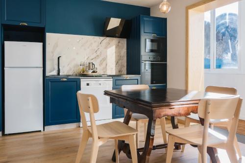 a kitchen with blue cabinets and a wooden table and chairs at Campanha Apartment By Porto Stories in Porto