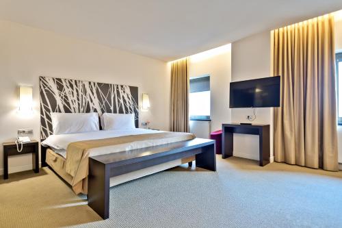 a hotel room with a large bed and a flat screen tv at Ramada Plaza by Wyndham Bucharest Convention Center in Bucharest