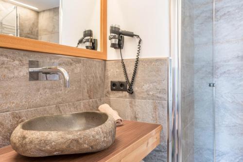 y baño con lavabo de piedra y ducha. en Guntschöllerhof Rotwand en Fiè