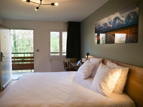 um quarto com uma cama com lençóis brancos e almofadas em Motel 991 em Viviers-du-Lac