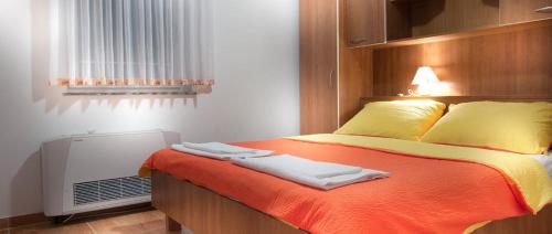 a bedroom with a bed with orange sheets and yellow pillows at Apartment in Novalja with sea view, terrace, air conditioning, WiFi 3565-1 in Novalja