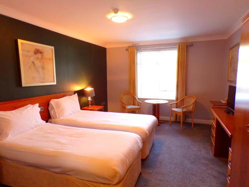 um quarto de hotel com duas camas e uma mesa em Fox and Goose Inn em Brent Knoll