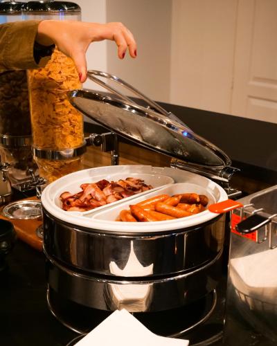 a person reaching for a plate of food in a pot at Motel 991 in Viviers-du-Lac
