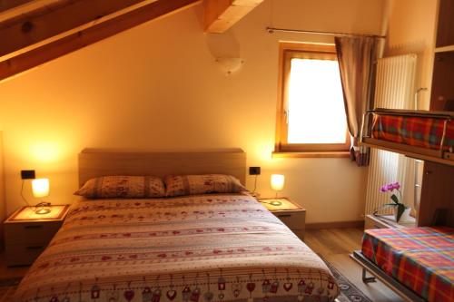 a bedroom with a bed and a window and two lamps at Casa dello Sciatore in Bormio