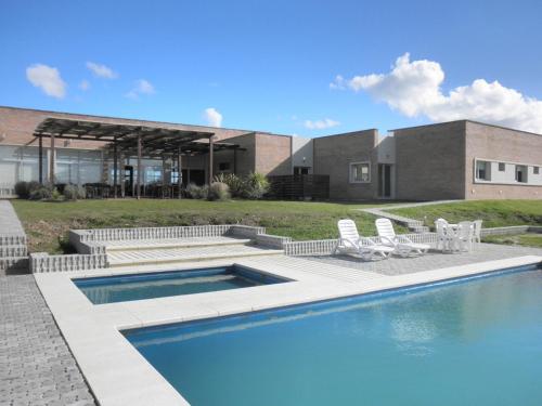 a house with a swimming pool and some chairs at Hotel Juana de Ibarbourou in Melo