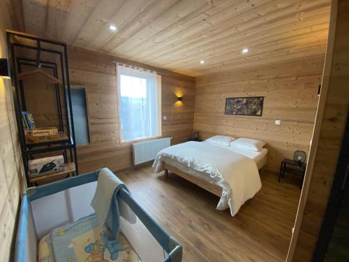 ein Schlafzimmer mit einem Bett in einem Holzzimmer in der Unterkunft Les Chalets Bambi & Jacuzzi privatif in La Bresse