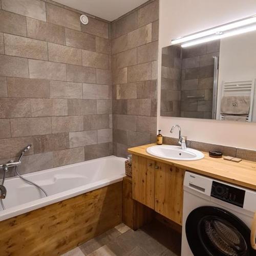 une salle de bain avec un lavabo et une machine à laver dans l'établissement Les Suites du Monetier, alliant le charme et l'authenticité d'un chalet de prestige au cœur du village, au Monêtier-les-Bains