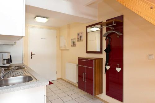 uma cozinha com uma porta vermelha e um lavatório em Kietzspeicher App 39 em Waren