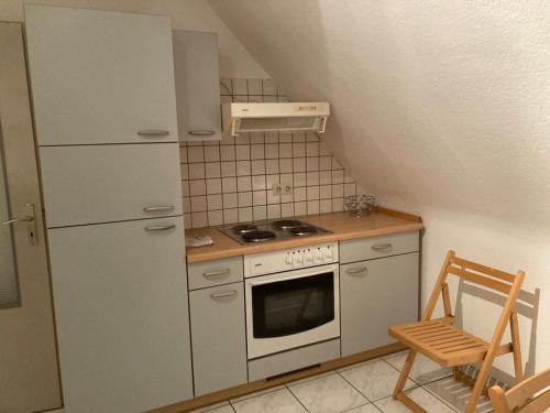 uma pequena cozinha com um fogão e uma cadeira em Monteurunterkunft Wiesental em Waghäusel