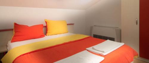łóżko z czerwonymi i żółtymi poduszkami w pokoju w obiekcie Apartment in Novalja with sea view, terrace, air conditioning, WiFi 3565-12 w Novalji
