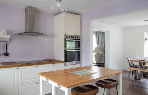 a kitchen with white cabinets and a wooden table at Ruadh in Ose