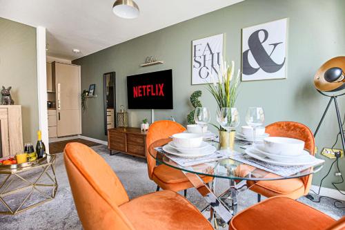 a dining room with a glass table and orange chairs at Luxury Apartment - City Centre - Free Parking, Fast Wifi, Sky TV and Netflix by Yoko Property in Milton Keynes