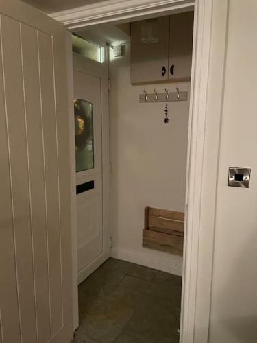 a hallway with a white door and a window at Brook Cottage in Holmfirth
